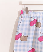 Pusheen Cherry Pajama Set includes a white and blue gingham oversized top and elastic waistband shorts. The set has an all over print of Pusheen the Cat leaping next to two dark pink cherries. 