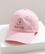 Sunlight shines on the Pusheen Cap to show off the light pink color of the cap. 