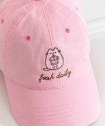 Fresh Daily Pusheen Sweets pink cap. The cat holds a cherry tiered mini cake. 