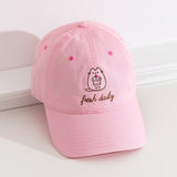 Top-down view of the Pusheen Sweets Cap. The top button and seams can be seen from this view as well as the thread detailing on the bill of the hat. The hat is propped on a white ledge to show the full size of the baseball-style cap. 