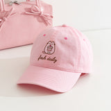 Fresh Daily Pusheen Sweets pink cap. The cat holds a cherry tiered mini cake. 