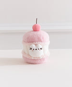 Front view of the Pusheen Sweets Cherry Macaron Plush. The removable white Pusheen plush sits within a macaron environment with a light pink cherry at the very top.  