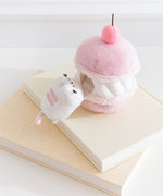 Side view of the Cherry Plush. The removable interior plush rests in front of the macaron environment. The little white cat plush has light pink embroidery details.  