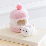 Side view of the Cherry Plush. The removable interior plush rests in front of the cake environment. The little white plush fits inside the front hole of the macaron plush.