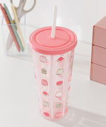 Pusheen water bottle with straw sits atop a desktop. The clear base as light pink hues at the top and bottom of the cup.