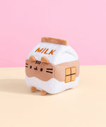 Back view of the Chocolate Milk Sips Plush. The back of the plush features the word ‘Milk’ in brown embroidery, plush back paws, and an extended white and brown striped tail. 