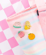 Pusheen Fruits Pin Set on a yellow background. Pusheen the Cat takes the form of a strawberry, banana, watermelon slice, and orange. The features of the pins are outlined in a shiny gold finish.