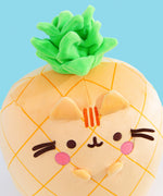 Front view of the Pusheen Fruits Scented Pineaplle Squisheen Plush. Pusheen the Cat is a yellow pineapple with a vibrant green crown that’s sitting atop a white tabletop.