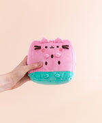 Side and back view of the Watermelon Fruit Plush. On the sides are brown circles to mimic watermelon seeds. On the back of the plush are embroidered red stripes to mimic Pusheen’s classic back stripes. Extending off the bottom back of the Pusheen is a pink and green striped tail. 