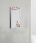 Back view of the Pusheen Magnetic Shopping List Notepad. The pink and purple cardboard backer card has two magnetic strips to ensure a strong hold. One magnet is near the top of the rectangular notepad while one magnet is near the bottom. 