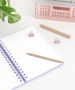 Back cover of the Pusheen notebook. The light purple notebook has a grid pattern. The elastic band to keep the notebook closed is attached on the corners of the back cover.